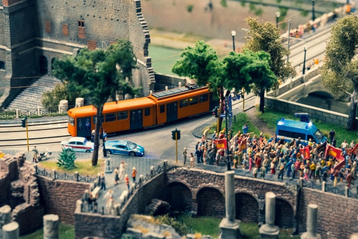 Miniature scene of a tram, crowd, police van, and historic building.