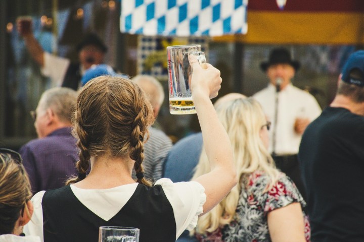 Person in a crowd raises a beer mug at a festive gathering.