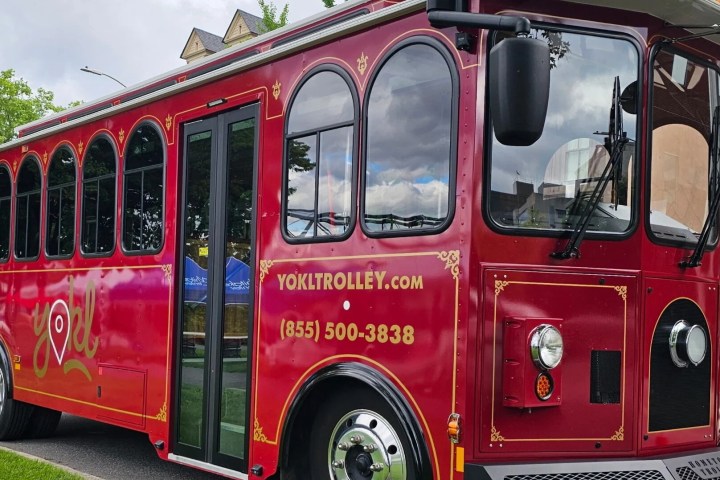 Red vintage-style trolley bus with gold accents parked on the street.